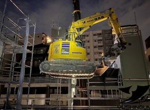 階上解体のために重機が吊り上げられている様子